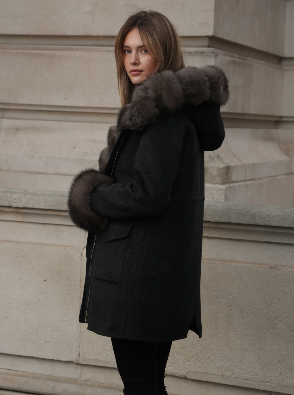 Side view of the dark grey merino wool coat with fox fur hood, cuffs and zip closure