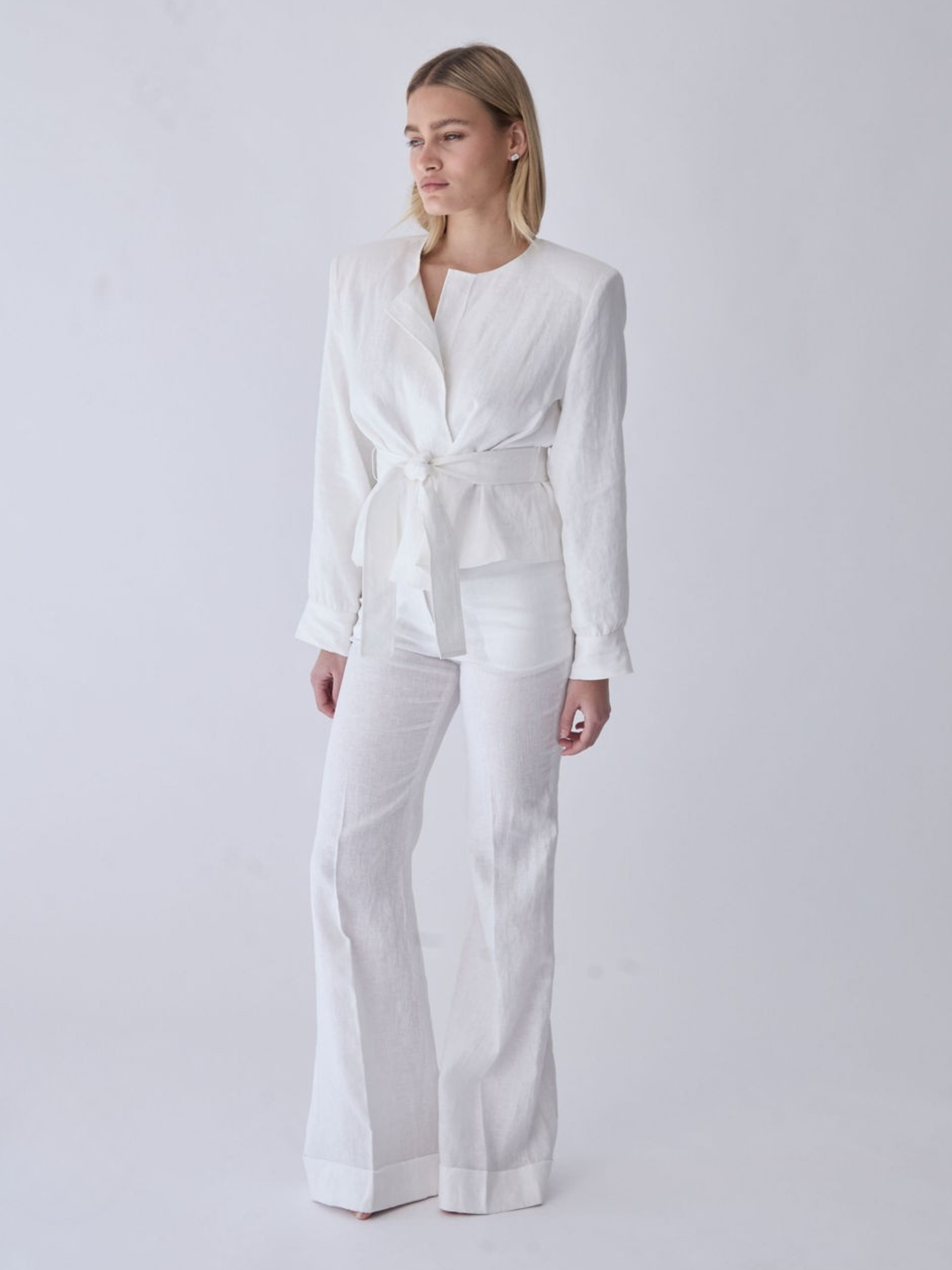 Heidi Linen Jacket with structured shoulder padding and tie-waist, styled with wide-leg linen trousers.