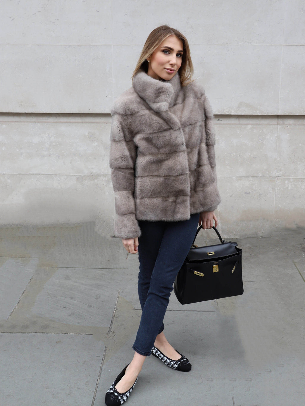 Full length look of The Alexandra Mink Jacket in grey styled with jeans, heels and a black handbag