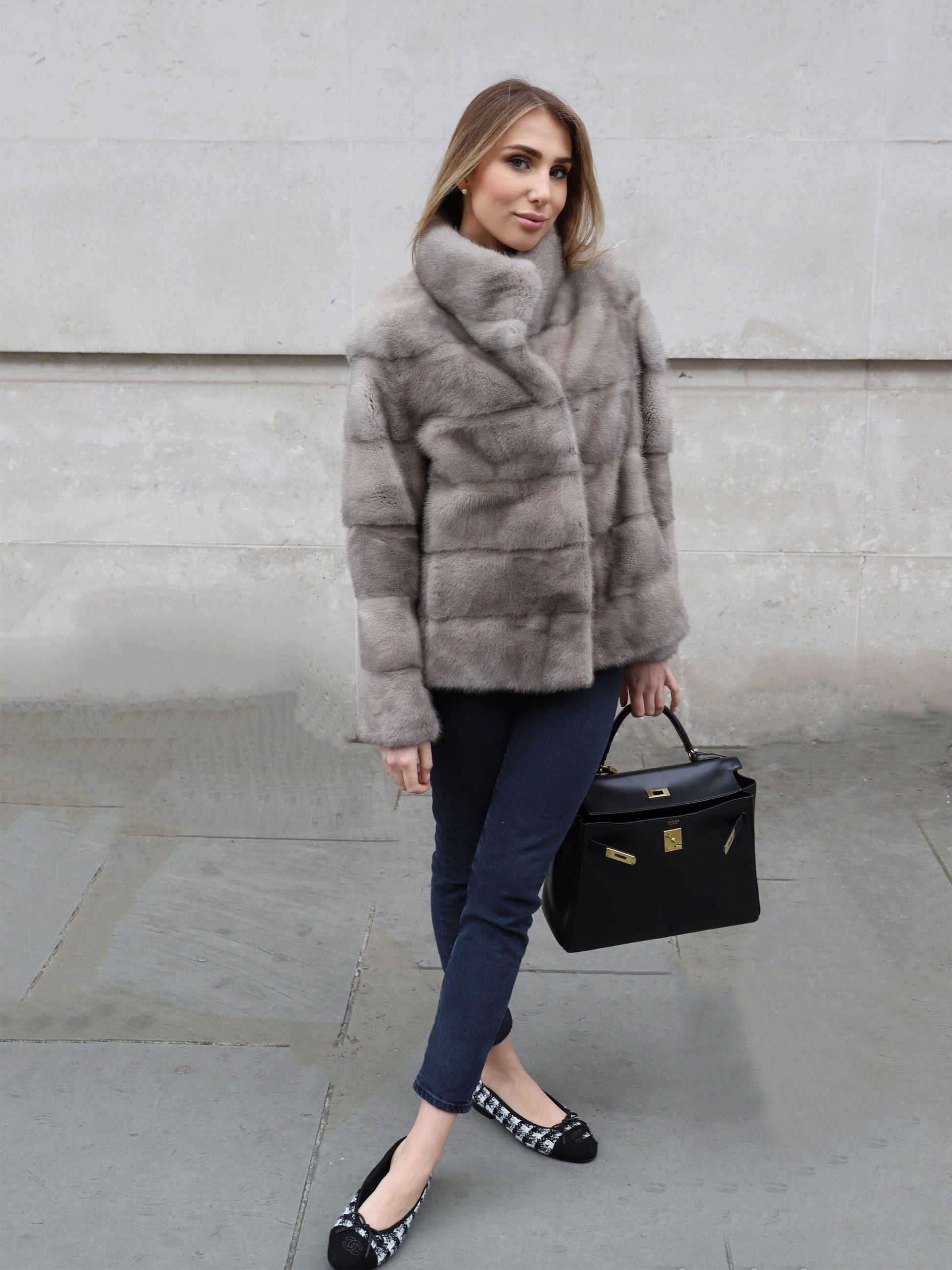 Full length look of The Alexandra Mink Jacket in grey styled with jeans, heels and a black handbag