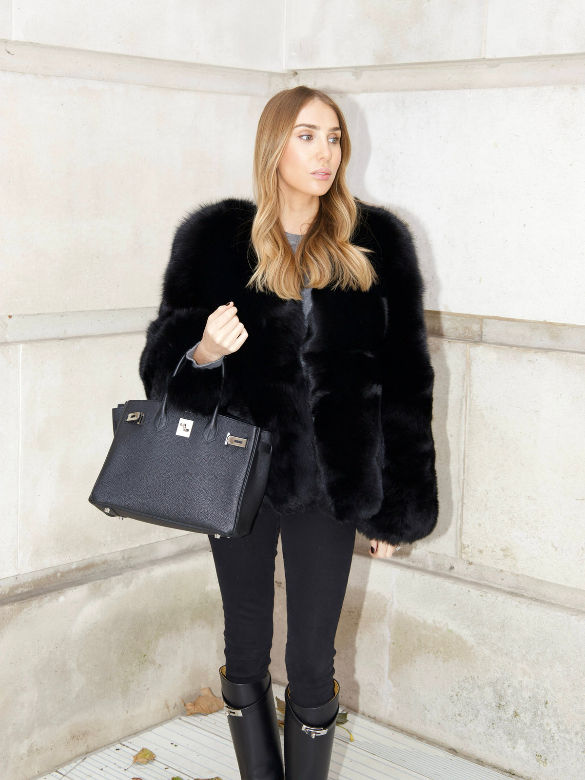 Full length look of The Anouska Fox Fur Coat in black styled with black trousers, boots and a handbag