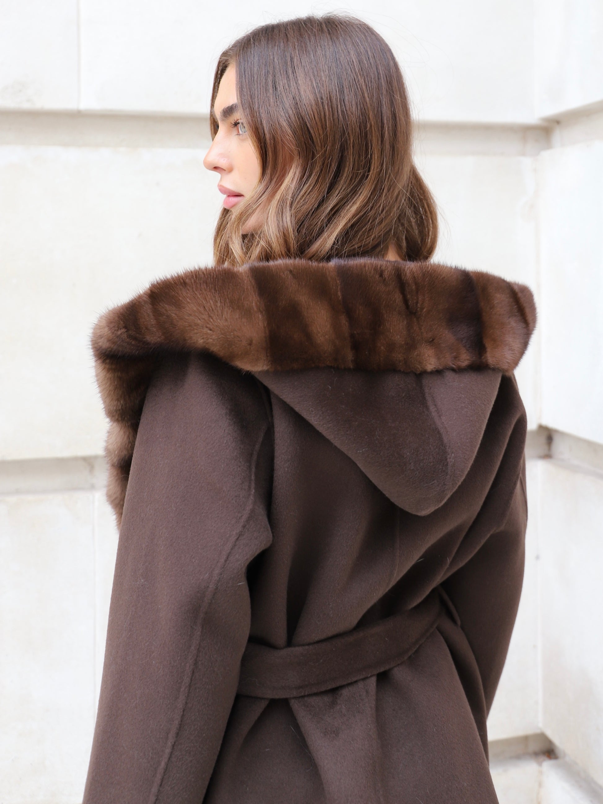 Back view of The Ayla Coat in chocolate brown showing hood, belt and mink fur trim