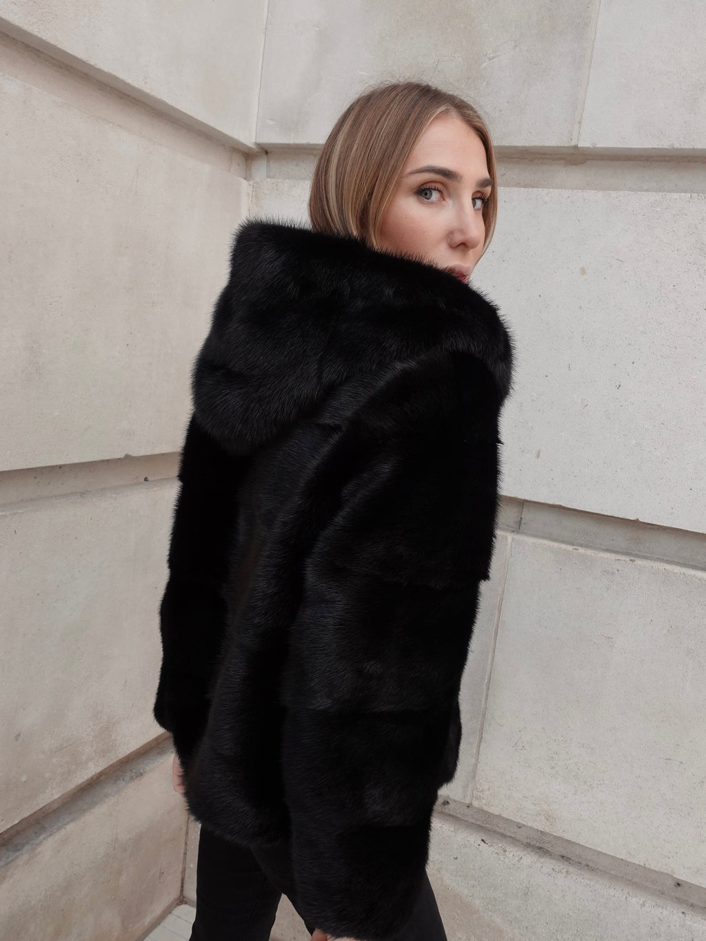 Back view of The Alexandra black mink coat showing the hood and relaxed silhouette