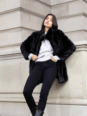 Woman in oversized brown fur coat with slim black jeans